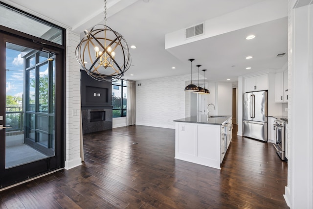 kitchen featuring white cabinetry, appliances with stainless steel finishes, a wealth of natural light, and an island with sink