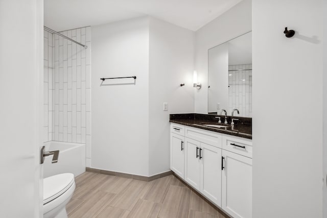 full bathroom featuring vanity, tiled shower / bath, and toilet