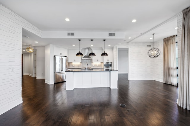 kitchen featuring white cabinetry, stainless steel appliances, decorative light fixtures, dark wood-type flooring, and a kitchen island with sink