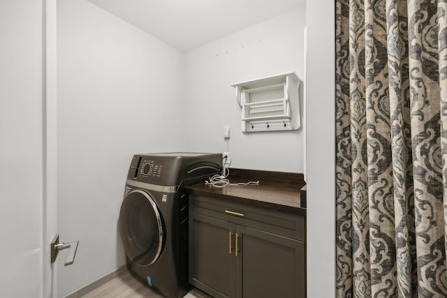 clothes washing area with light hardwood / wood-style floors, washer / clothes dryer, and cabinets