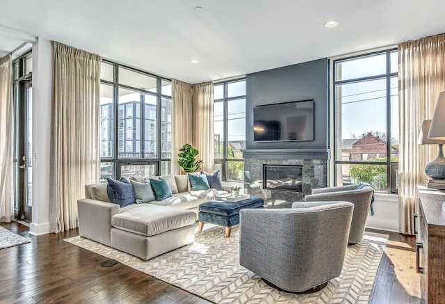 living room with expansive windows, hardwood / wood-style floors, and a large fireplace