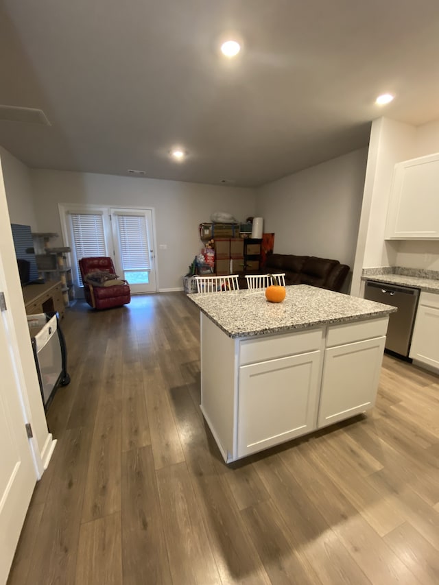 kitchen featuring white cabinetry, light stone countertops, dishwasher, light hardwood / wood-style floors, and a center island