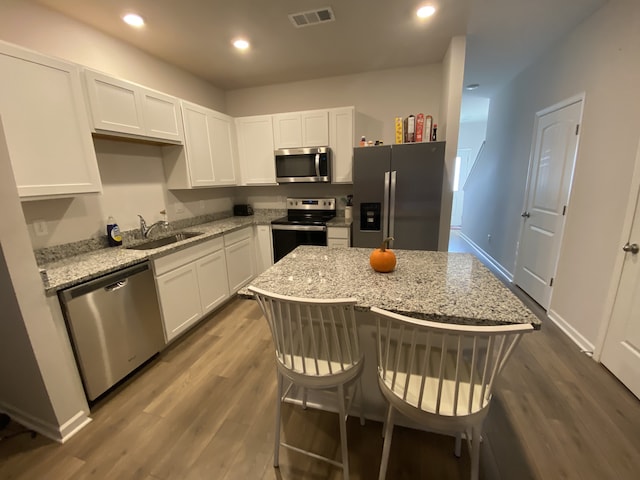 kitchen featuring dark wood-type flooring, light stone counters, stainless steel appliances, and sink