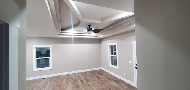 empty room featuring ceiling fan, a raised ceiling, and light wood-type flooring