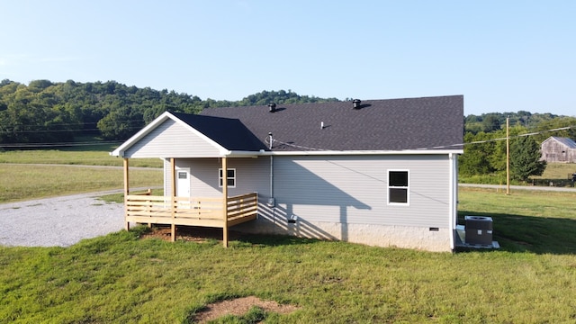 back of house with central air condition unit, a lawn, and a wooden deck