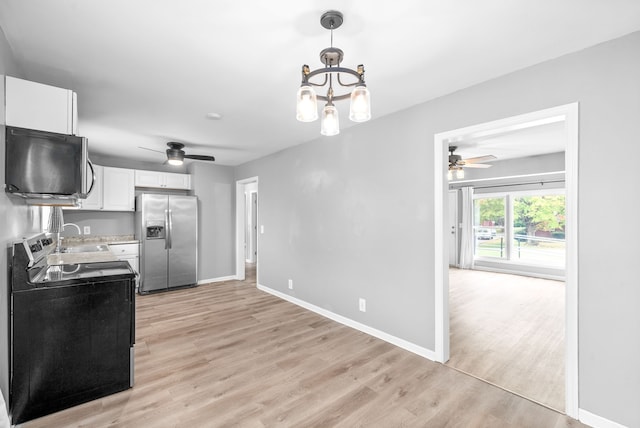 kitchen with black electric range oven, light hardwood / wood-style flooring, stainless steel fridge, decorative light fixtures, and white cabinets