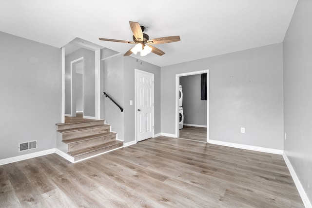 interior space with stacked washer / drying machine, light hardwood / wood-style flooring, and ceiling fan