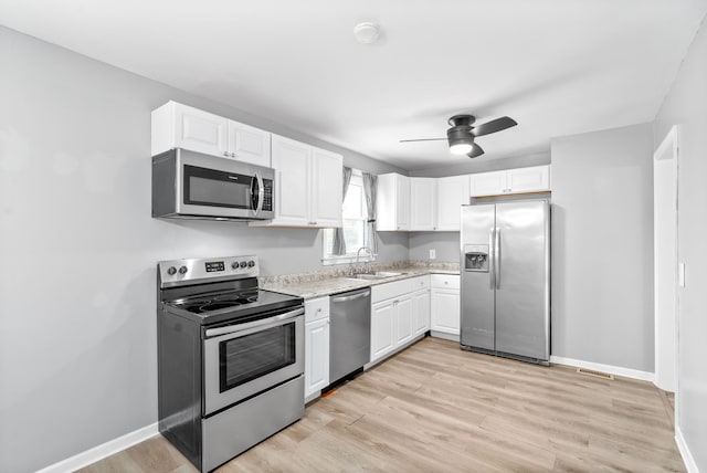 kitchen featuring white cabinets, ceiling fan, appliances with stainless steel finishes, light hardwood / wood-style flooring, and sink