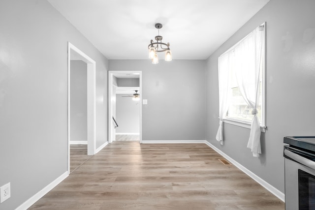 unfurnished dining area featuring light hardwood / wood-style floors and ceiling fan with notable chandelier