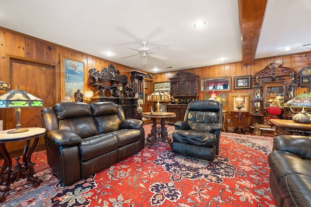 living room with ceiling fan, wood walls, and beam ceiling