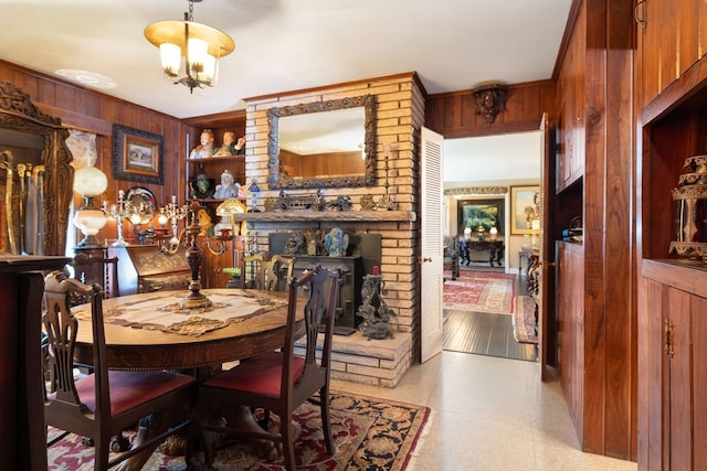 dining area featuring wood walls, a chandelier, and a fireplace