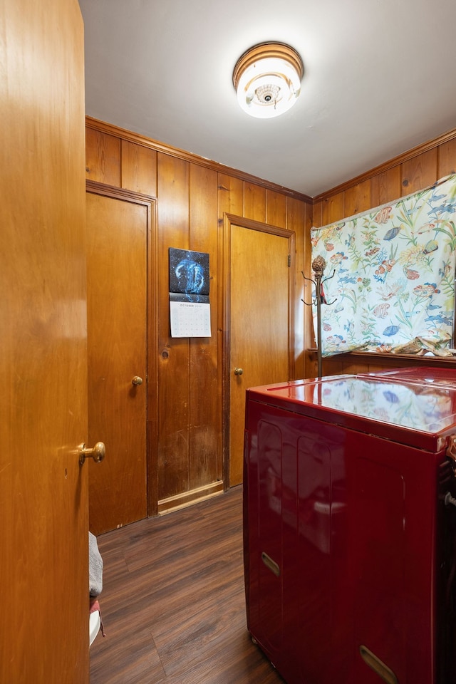 laundry room featuring washing machine and dryer, dark hardwood / wood-style floors, and wooden walls