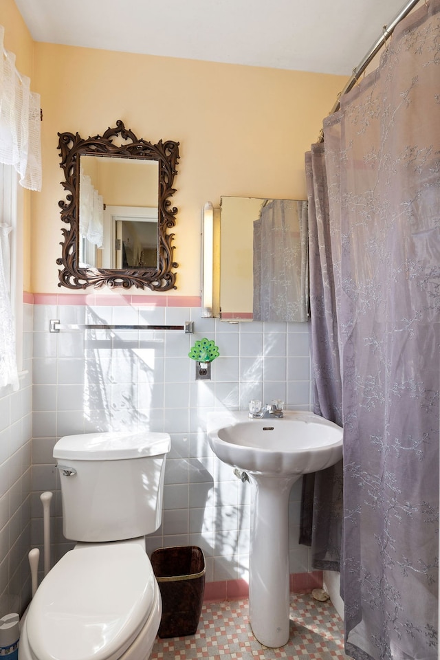 bathroom featuring tile walls, curtained shower, and toilet