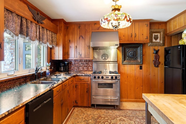 kitchen with wood walls, black appliances, sink, decorative light fixtures, and exhaust hood