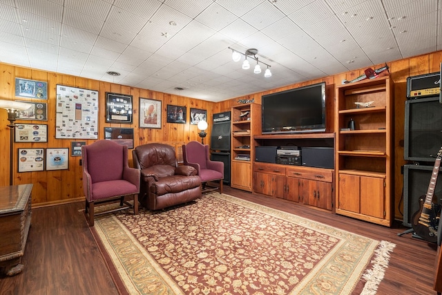 living room featuring dark hardwood / wood-style flooring, wooden walls, and built in shelves