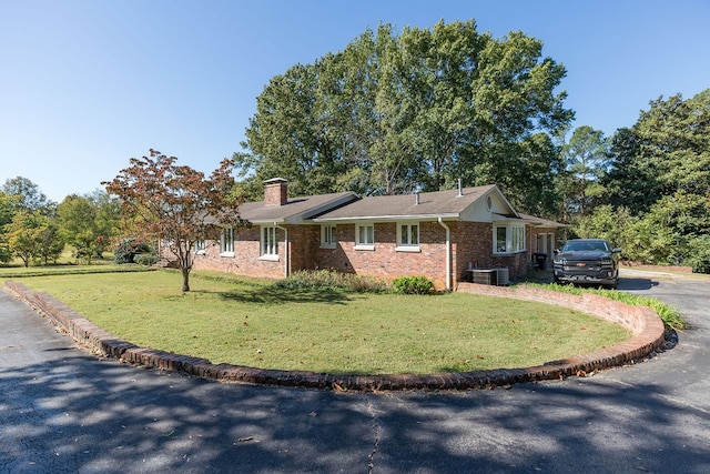 ranch-style home with a front lawn and central AC unit