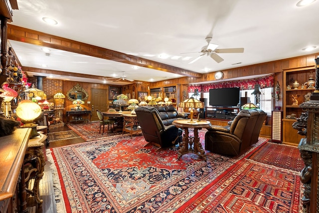 living room with ceiling fan, wood walls, and wood-type flooring