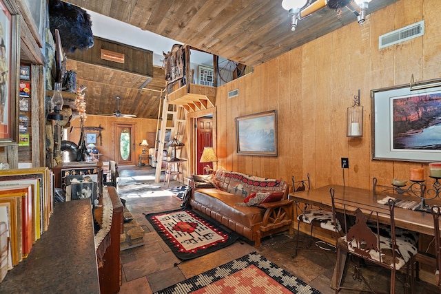 sitting room with wood ceiling, wooden walls, high vaulted ceiling, and ceiling fan