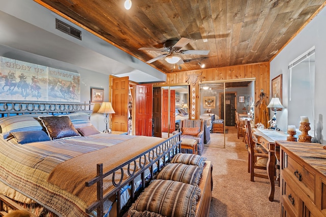 carpeted bedroom featuring wood ceiling, wood walls, two closets, and ceiling fan