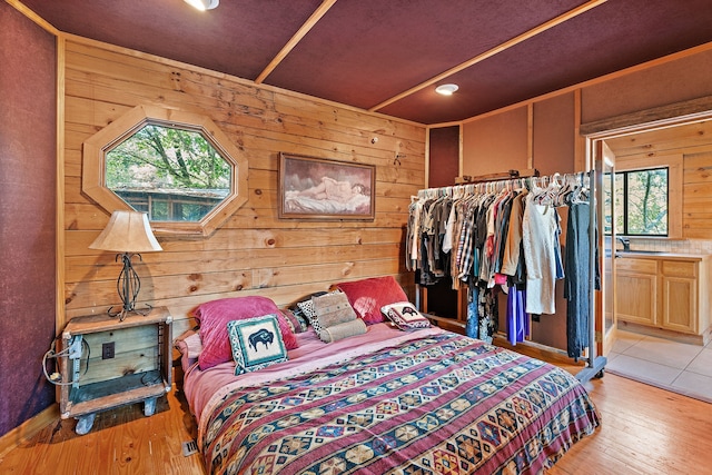 bedroom featuring wooden walls, sink, and light wood-type flooring