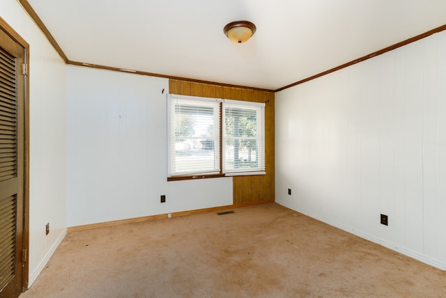 carpeted empty room with ornamental molding and wooden walls