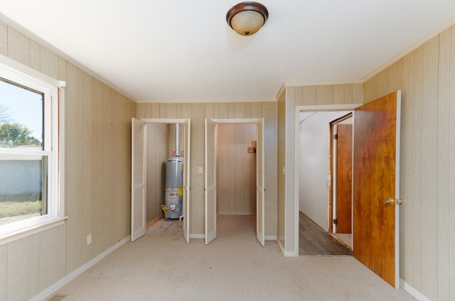 unfurnished bedroom with light carpet, crown molding, and water heater