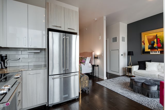 kitchen with backsplash, light stone counters, high quality fridge, dark wood-type flooring, and stovetop