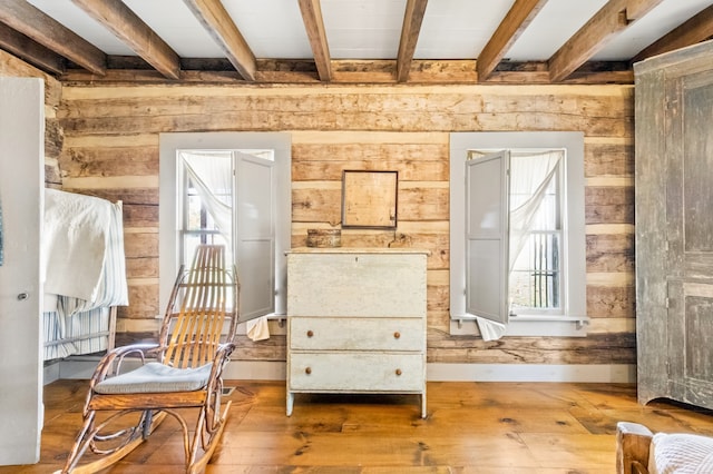 sitting room featuring beam ceiling, wood walls, and hardwood / wood-style flooring