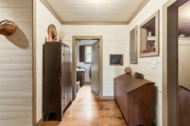 corridor with light hardwood / wood-style flooring and wood walls