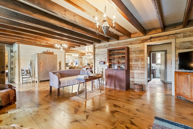 living room with light hardwood / wood-style floors, wood walls, beamed ceiling, and a chandelier