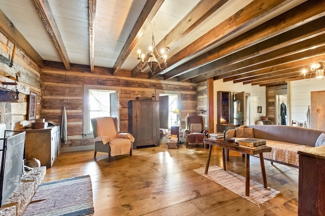 living area with light hardwood / wood-style floors, beamed ceiling, a wealth of natural light, and an inviting chandelier