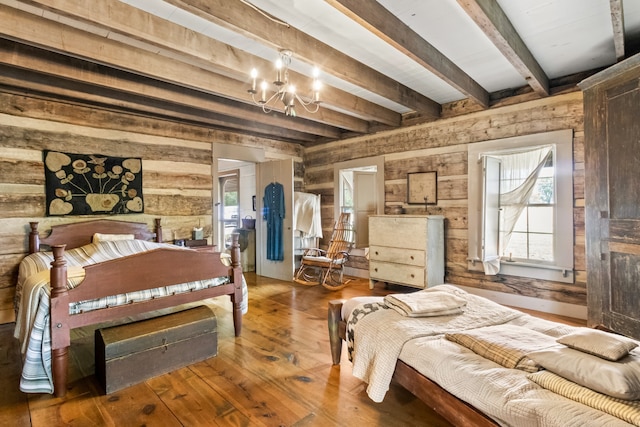 bedroom featuring beam ceiling, hardwood / wood-style floors, a notable chandelier, and wood walls