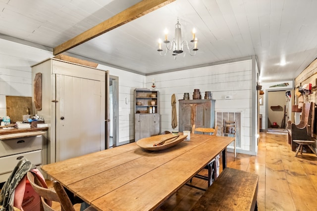 dining area featuring beamed ceiling, a notable chandelier, light wood-type flooring, and wood walls