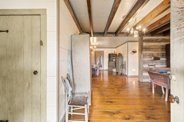 interior space with hanging light fixtures, a chandelier, wood-type flooring, wood walls, and beamed ceiling