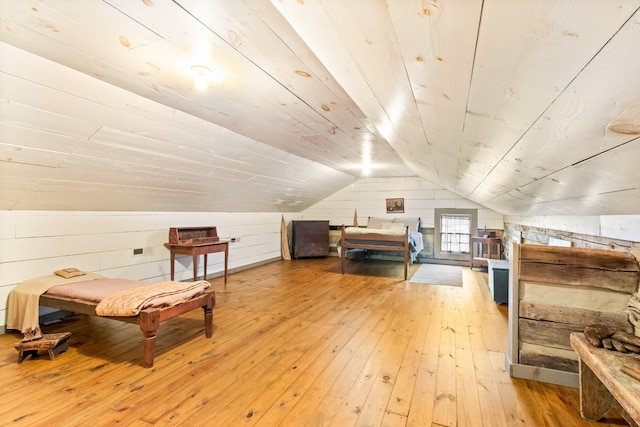 additional living space with lofted ceiling, wooden walls, and hardwood / wood-style floors