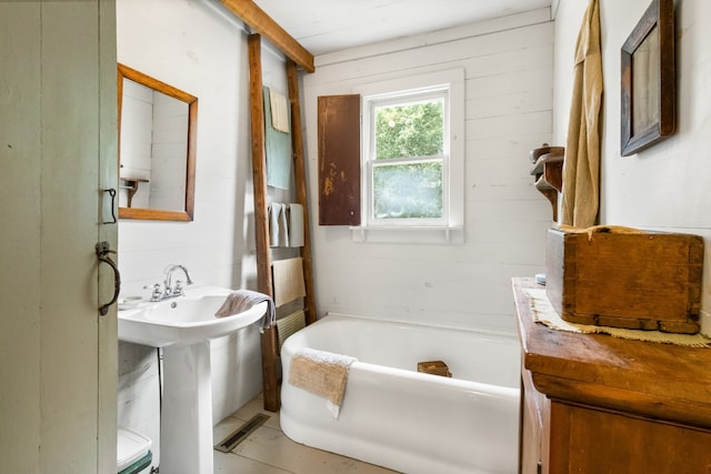 bathroom featuring wooden walls and a bath