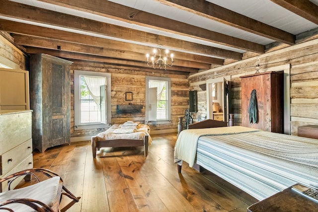 bedroom featuring a chandelier, multiple windows, light hardwood / wood-style floors, and wood walls