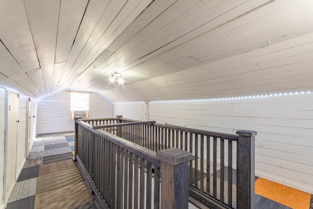 hallway featuring wood ceiling, vaulted ceiling, wooden walls, and dark carpet