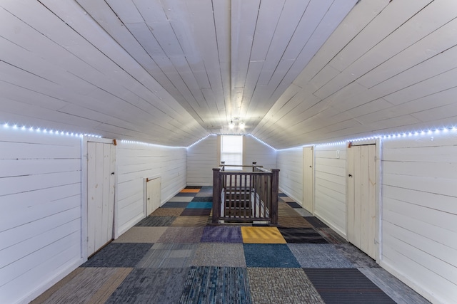 additional living space with wood walls, wooden ceiling, and lofted ceiling