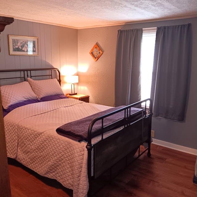 bedroom featuring ornamental molding, a textured ceiling, and wood-type flooring