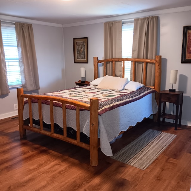 bedroom featuring crown molding, multiple windows, and dark hardwood / wood-style flooring