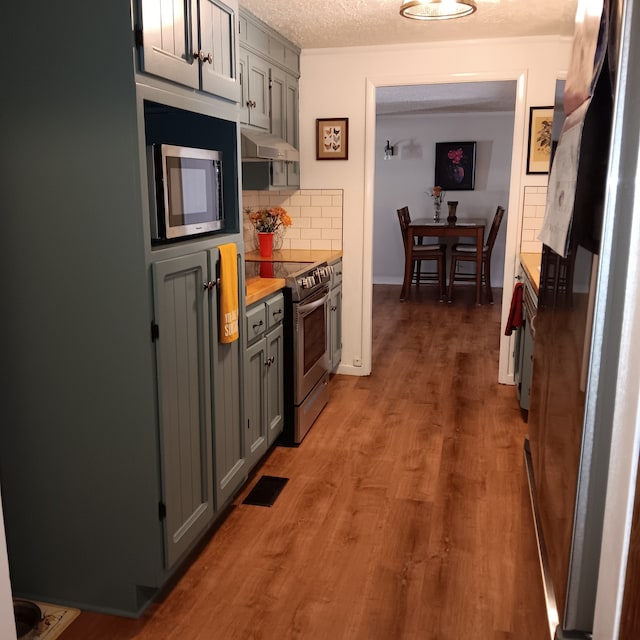 kitchen featuring backsplash, appliances with stainless steel finishes, gray cabinetry, and dark hardwood / wood-style floors