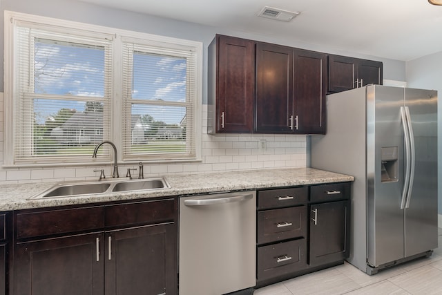 kitchen with appliances with stainless steel finishes, light tile patterned flooring, sink, dark brown cabinetry, and decorative backsplash