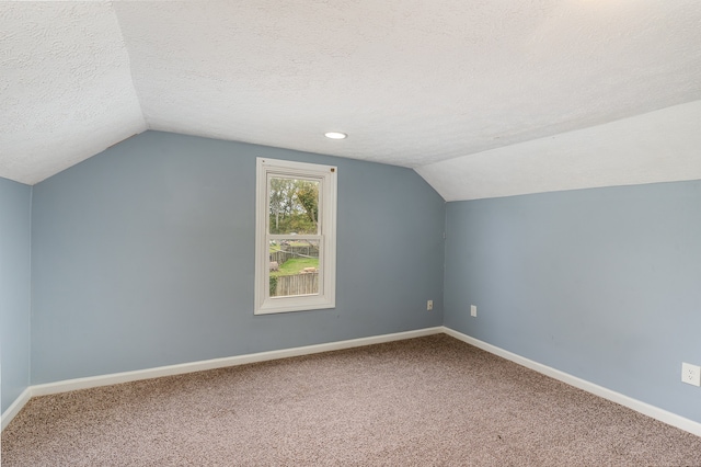 additional living space with a textured ceiling, lofted ceiling, and carpet floors