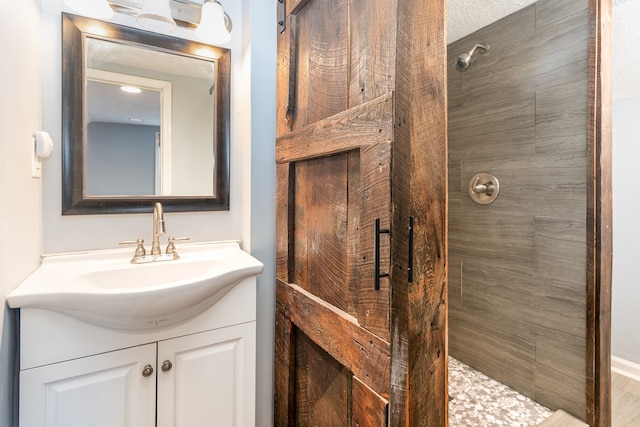 bathroom with vanity, a textured ceiling, and a tile shower