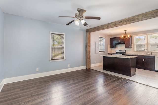 kitchen with stainless steel range with electric cooktop, a center island, beamed ceiling, decorative light fixtures, and dark wood-type flooring