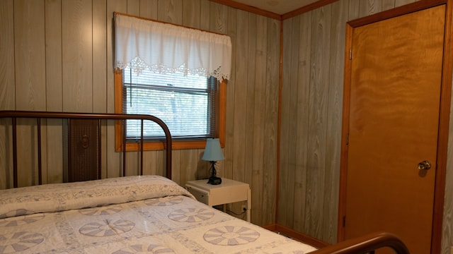 bedroom with ornamental molding and wooden walls