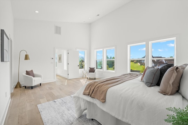 bedroom with high vaulted ceiling and light hardwood / wood-style flooring