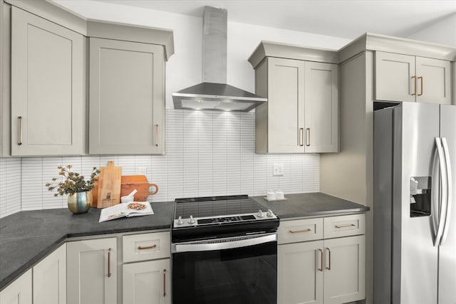 kitchen with gray cabinetry, tasteful backsplash, appliances with stainless steel finishes, wall chimney exhaust hood, and dark stone countertops