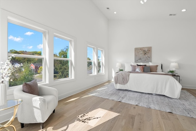 bedroom featuring light hardwood / wood-style floors and high vaulted ceiling